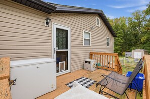 A single-story house with a deck, a refrigerator, a washing machine, and a small shed in the backyard. - Paws & Relax | Fredericksburg Home with Fire Pit (Fredericksburg)