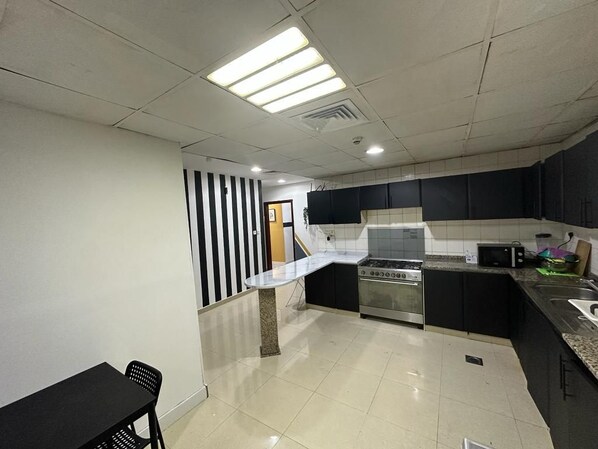 Una cocina moderna con estufa, microondas y armarios negros.