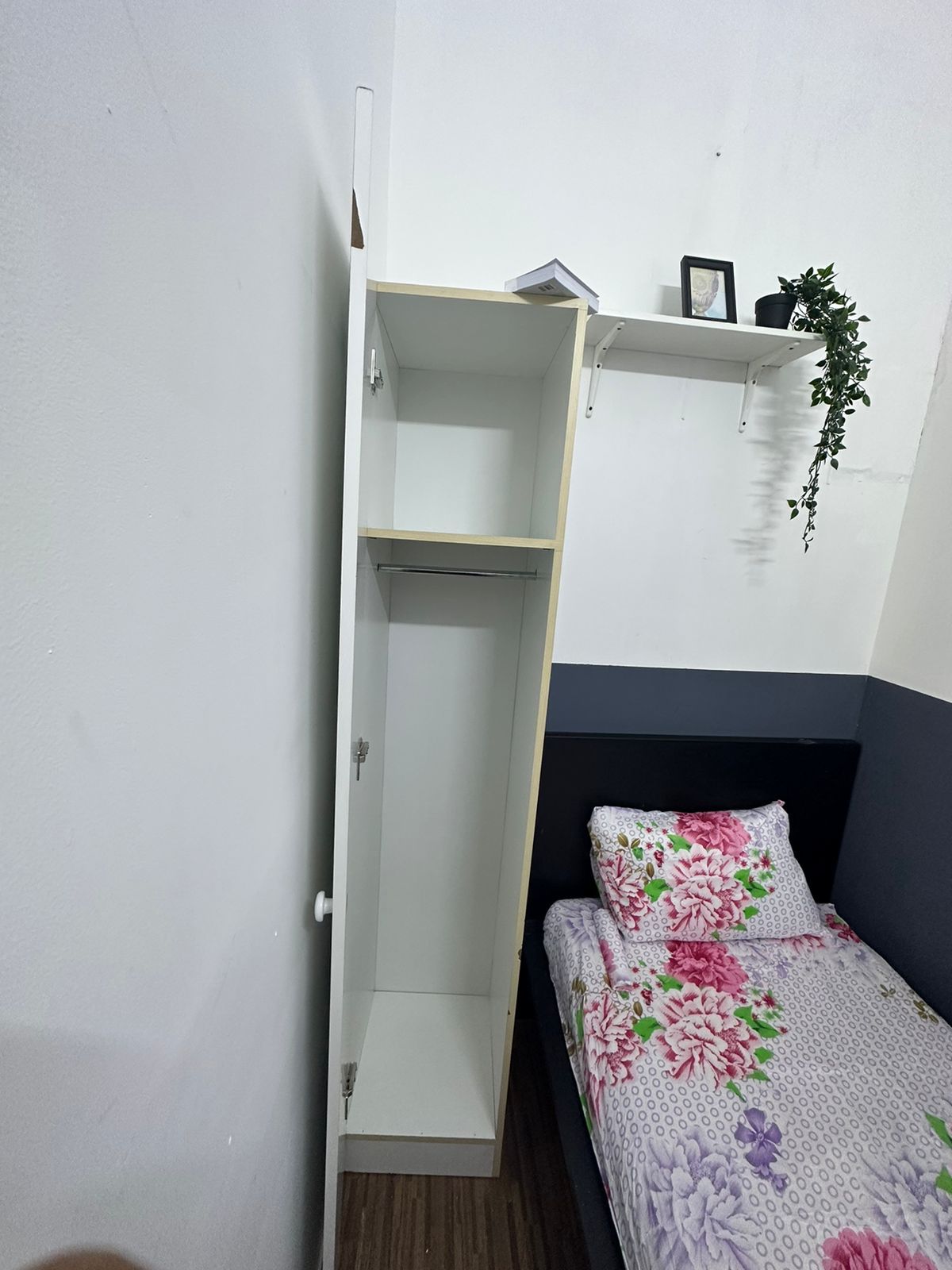 Een slaapkamer met een bed, een kledingkast en een plank met een plant.