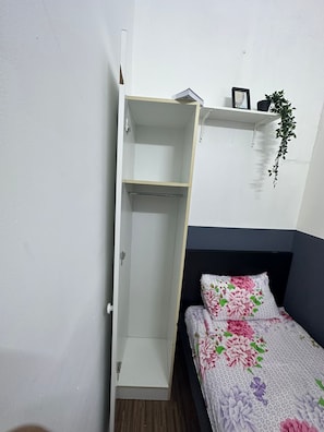 Een slaapkamer met een bed, een kledingkast en een plank met een plant.