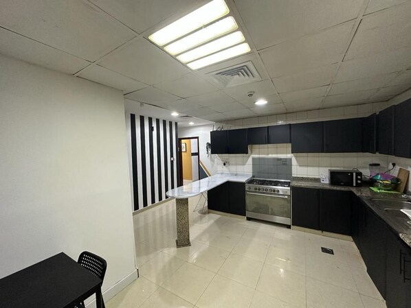 A kitchen with a stove, microwave, and a dining area with a table and chairs.