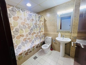 Een badkamer met toilet, wastafel en douchegordijn met bladmotief.