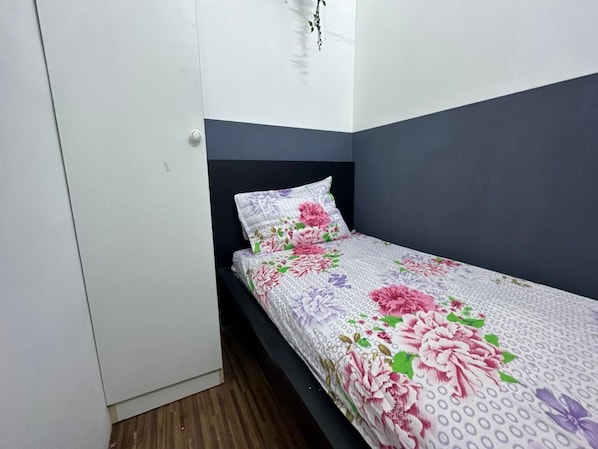 A single bed with a floral bedspread in a room with white walls and a dark headboard. - Euphoria Partition Room in Al Barsha1 (Dubai)