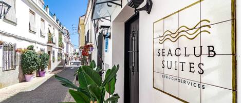 Straatbeeld van Seaclub Suites, met een strak gevel, een deur en een naambord.