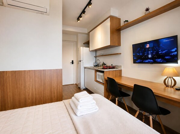 Une chambre d’hôtel équipée d’un lit, d’un bureau, d’une télévision et d  ’une kitchenette.