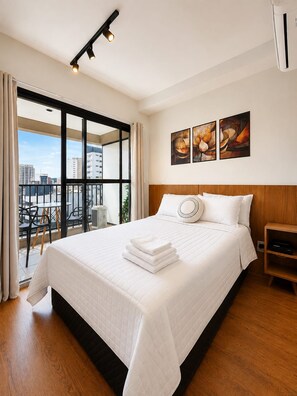 A hotel room with a large bed, a city view, and artwork on the wall. - SETIN 1504 (São Paulo)