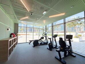 Ein modernes Fitnessstudio mit Trainingsgeräten, großen Fenstern und einem außergewöhnlichen Deckenstil.