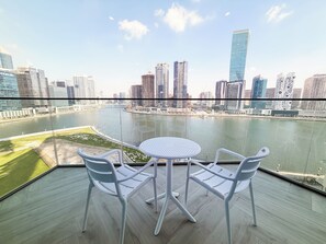 A balcony with a table and chairs overlooking a cityscape and a river. - Beautiful 2BR apartment in Peninsula Three, Breathtaking Canal view (Dubai)
