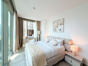 Ein modernes Hotelzimmer mit einem großen Bett, Nachttischen, einer Lampe und einem Fenster mit Vorhängen.