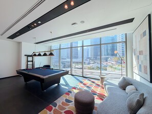 Ein modernes Zimmer mit einem Billardtisch, einer Couch und großen Fenstern mit Blick auf die Stadt.