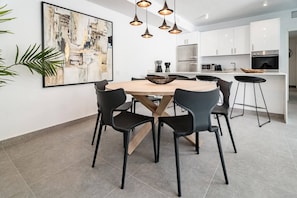 A modern kitchen with white cabinets, a central island with stools, and a dining table with chairs. - AB3 - Spacious holiday home, Puerto Banus (Marbella)