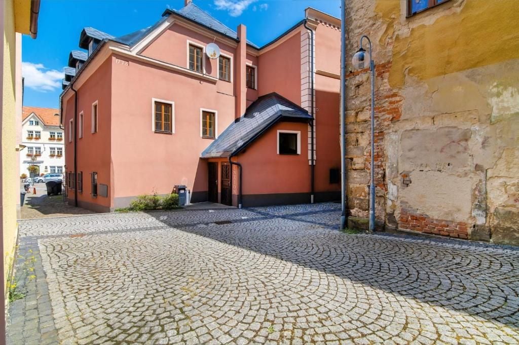 Une rue pavée menant à un bâtiment à la façade rouge et au toit noir.