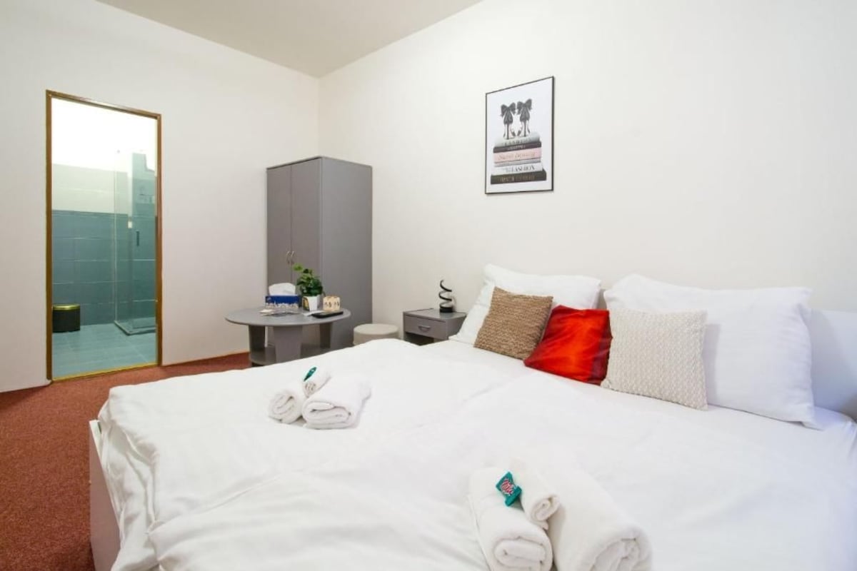 Een hotelkamer met een bed, een bureau, een stoel, een spiegel en een lijst met een foto aan de muur.