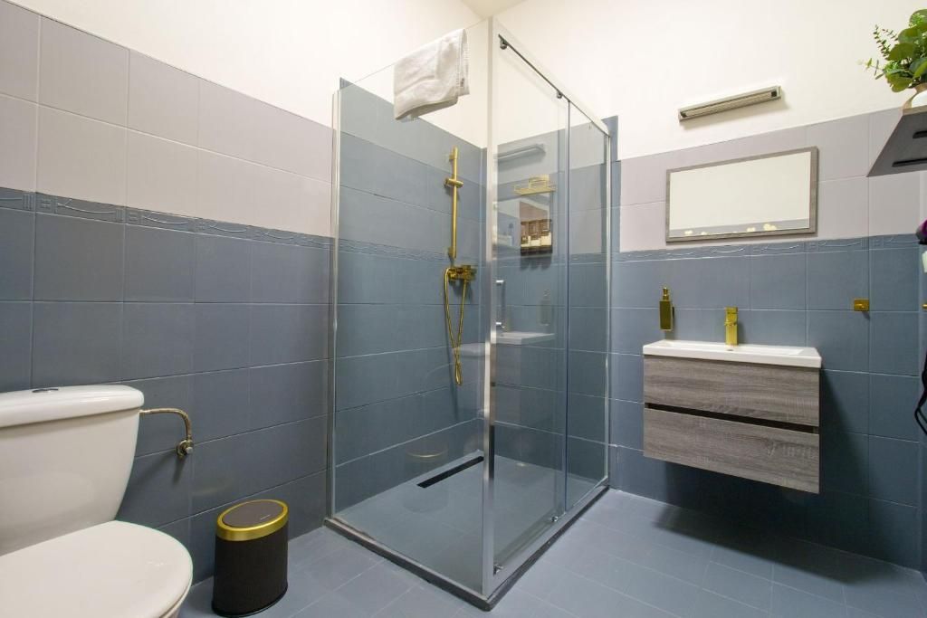 Une salle de bain avec une douche à parois de verre, des toilettes, un lavabo avec un miroir et une poubelle.
