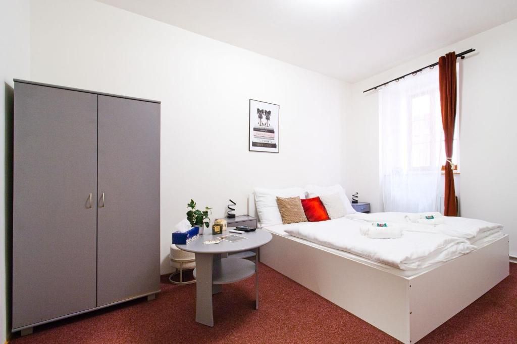 A bedroom with a bed, a wardrobe, a small round table, and a wall-mounted picture.