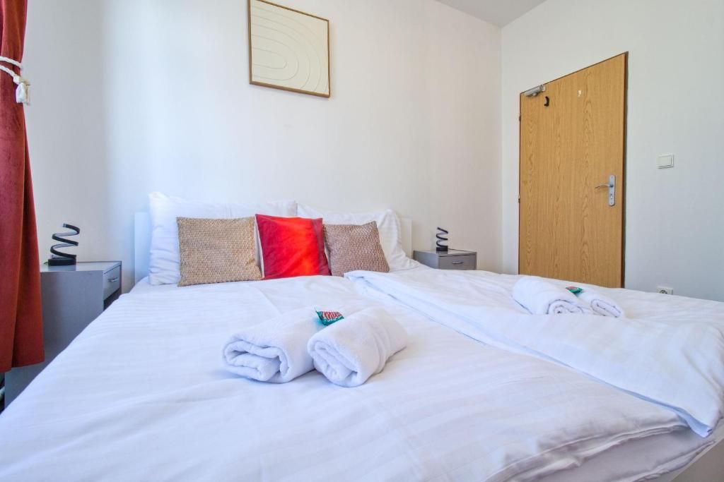A hotel room with a neatly made bed, a wooden door, and a framed picture on the wall.