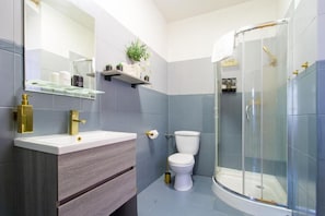 Een moderne badkamer met een witte wasbak, toilet en een douche met glazen wanden.