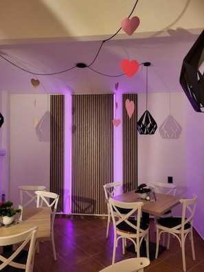 Een eetgedeelte met een houten tafel en witte stoelen, een gestreepte wand en hartvormige decoraties.