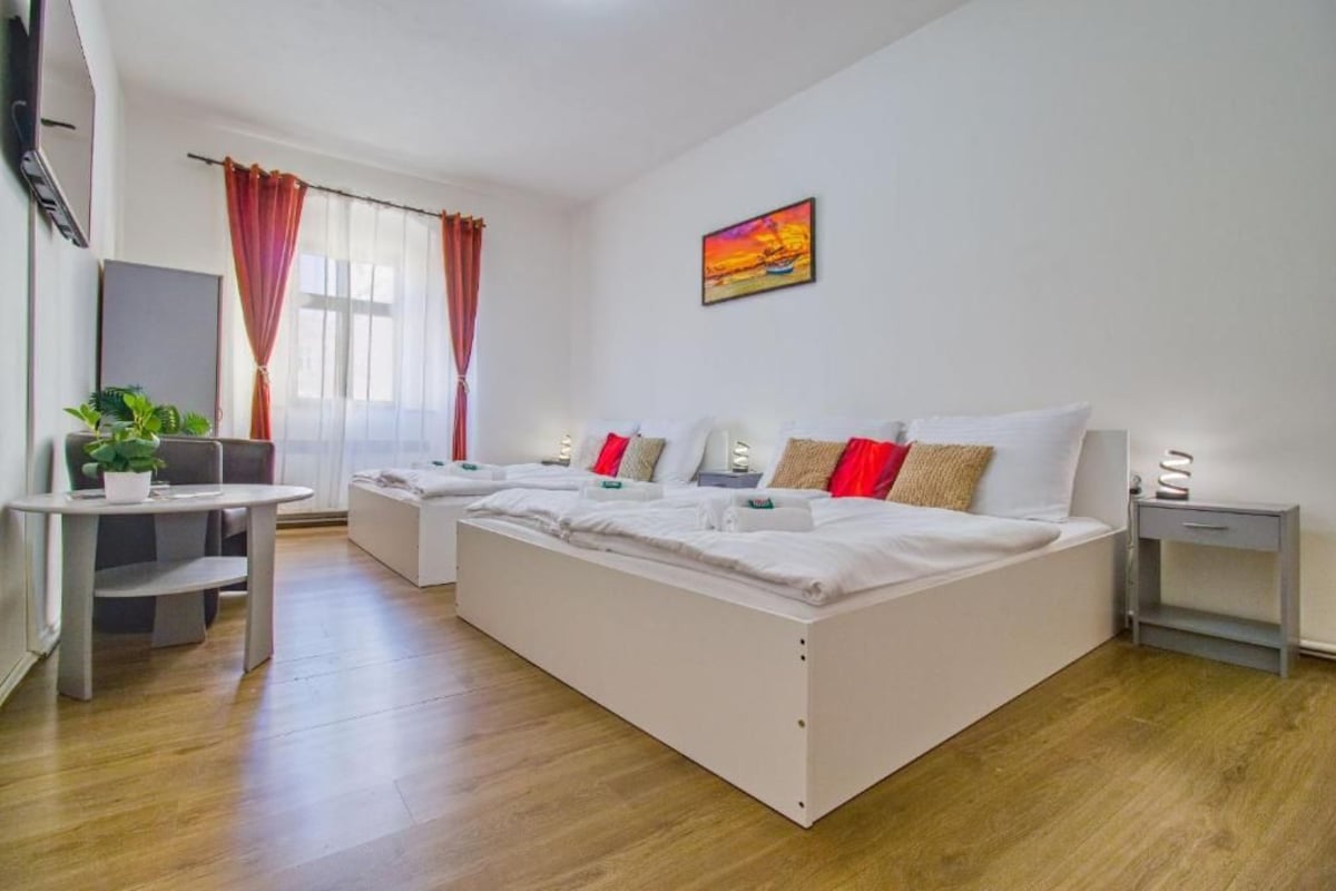 Een hotelkamer met een groot bed, een bureau, een stoel, een televisie en een raam met gordijnen.