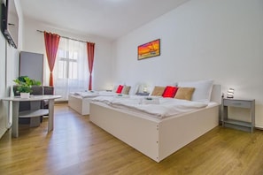 Een hotelkamer met een groot bed, een bureau, een stoel, een televisie en een raam met gordijnen.