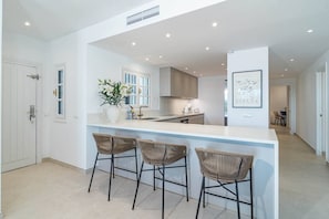 A modern kitchen with a central island, bar stools, and a dining area. - AB26 - Lovely holiday home in Aldea Blanca (Marbella)