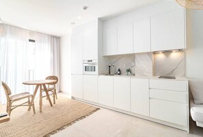 A modern kitchen with white cabinetry, a built-in oven, and a marble backsplash. - Seaclub suites by Roomservices (Estepona)