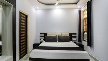 Un dormitorio con una cama, un ventilador de techo y una ventana con cortinas.