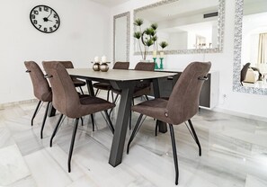 A dining area with a round table, six chairs, a wall clock, and a mirror with a decorative frame. - AB4 - Lovely holiday home walking distance, beach (Marbella)