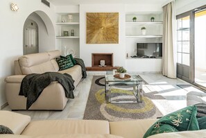 A modern living room with a sofa, coffee table, fireplace, and a large abstract painting. - AB4 - Lovely holiday home walking distance, beach (Marbella)