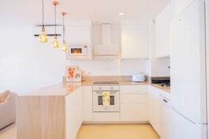 A modern kitchen with white cabinetry, a built-in oven, a microwave, and a toaster. - AC152 - Top Renovated Modern 1 Bed with Pool (Marbella)