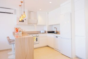 A modern kitchen with white cabinetry, a wooden countertop, a built-in oven, and a hanging light fixture. - AC152 - Top Renovated Modern 1 Bed with Pool (Marbella)