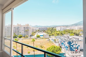 A view from a window overlooking a cityscape with buildings, a parking lot, and a clear sky. - AC152 - Top Renovated Modern 1 Bed with Pool (Marbella)