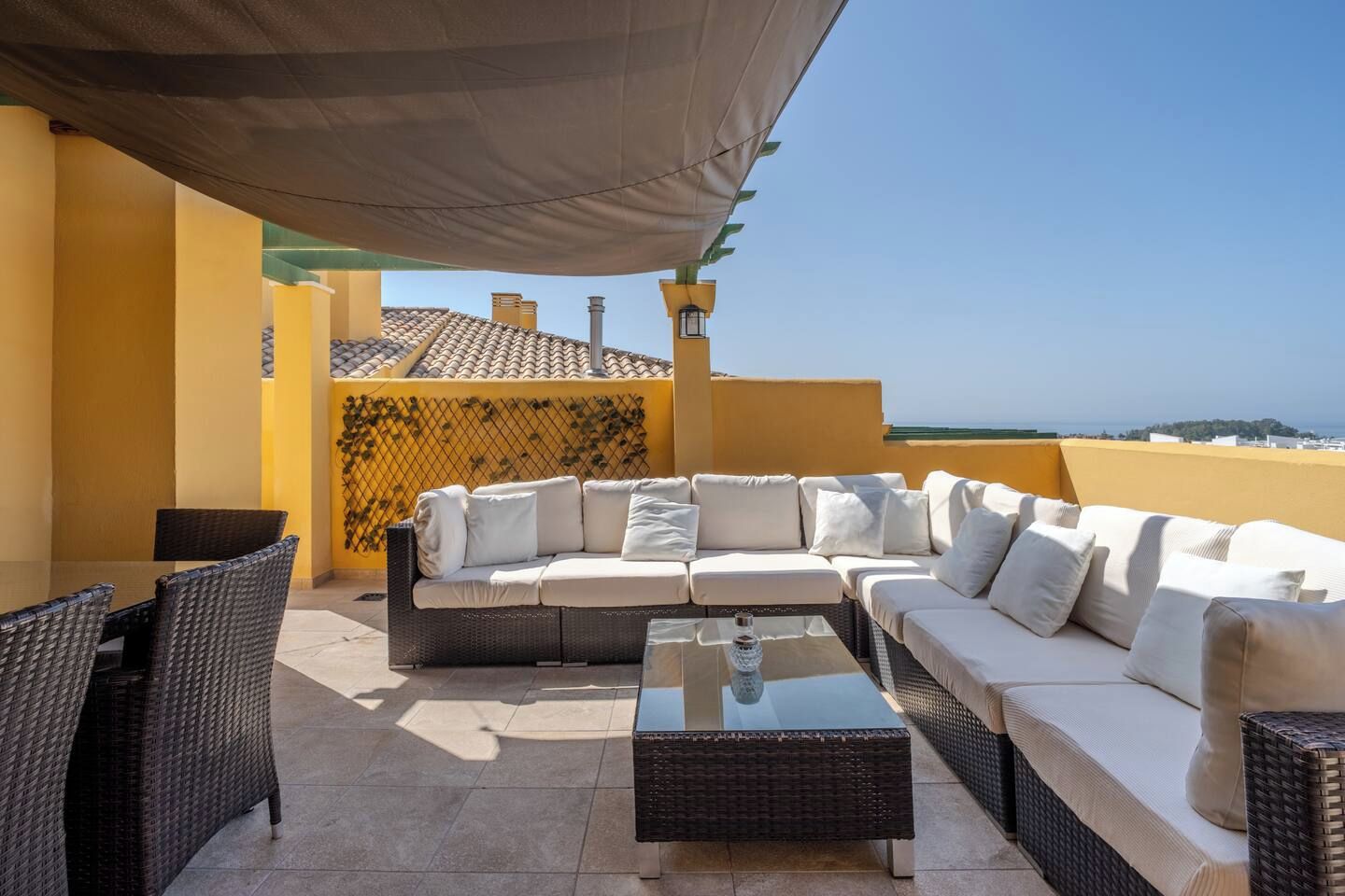 A rooftop terrace with a sofa, chairs, and a table.