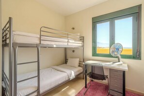 Ein Schlafraum mit Etagenbetten, einem Schreibtisch, einem Stuhl und einem Fenster mit Blick.