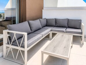 A sectional sofa with cushions, a wooden coffee table, and a glass door leading to an outdoor area. - AH2B - Modern apartment near Estepona town (Estepona)