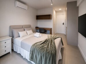 Ein modernes Hotelzimmer mit Bett, Nachttisch und Schreibtisch mit Stuhl.