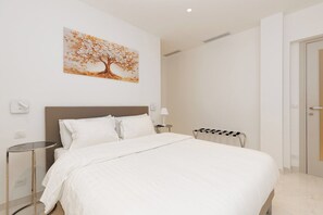 A hotel room with a bed, a bedside table, a lamp, a wall-mounted artwork, and a door. - Croisette : chic 2 chambres/ 2 salles de bains (Cannes)