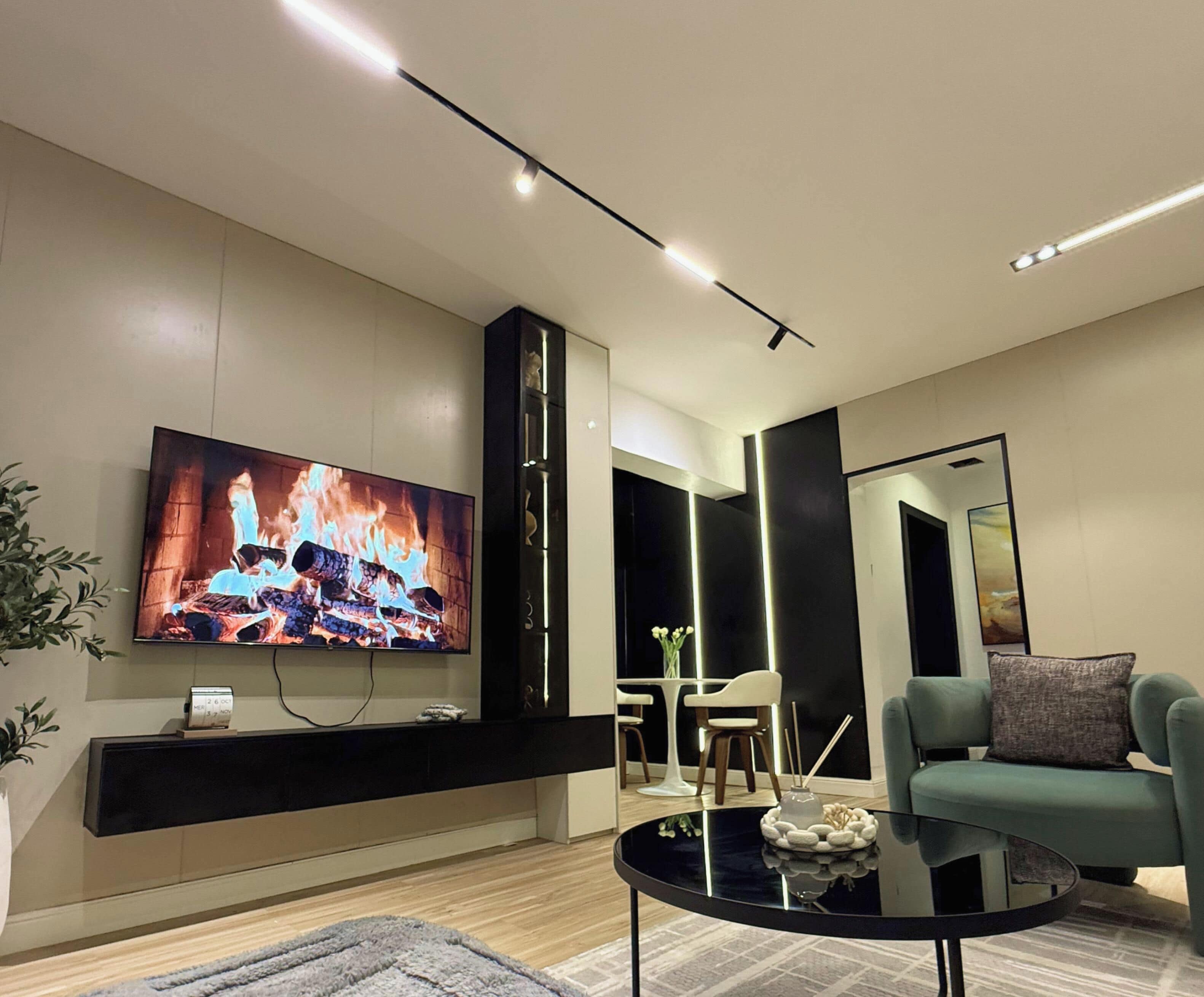 Ein modernes Wohnzimmer mit Flachbildfernseher, Kamin, Sofa und Couchtisch.