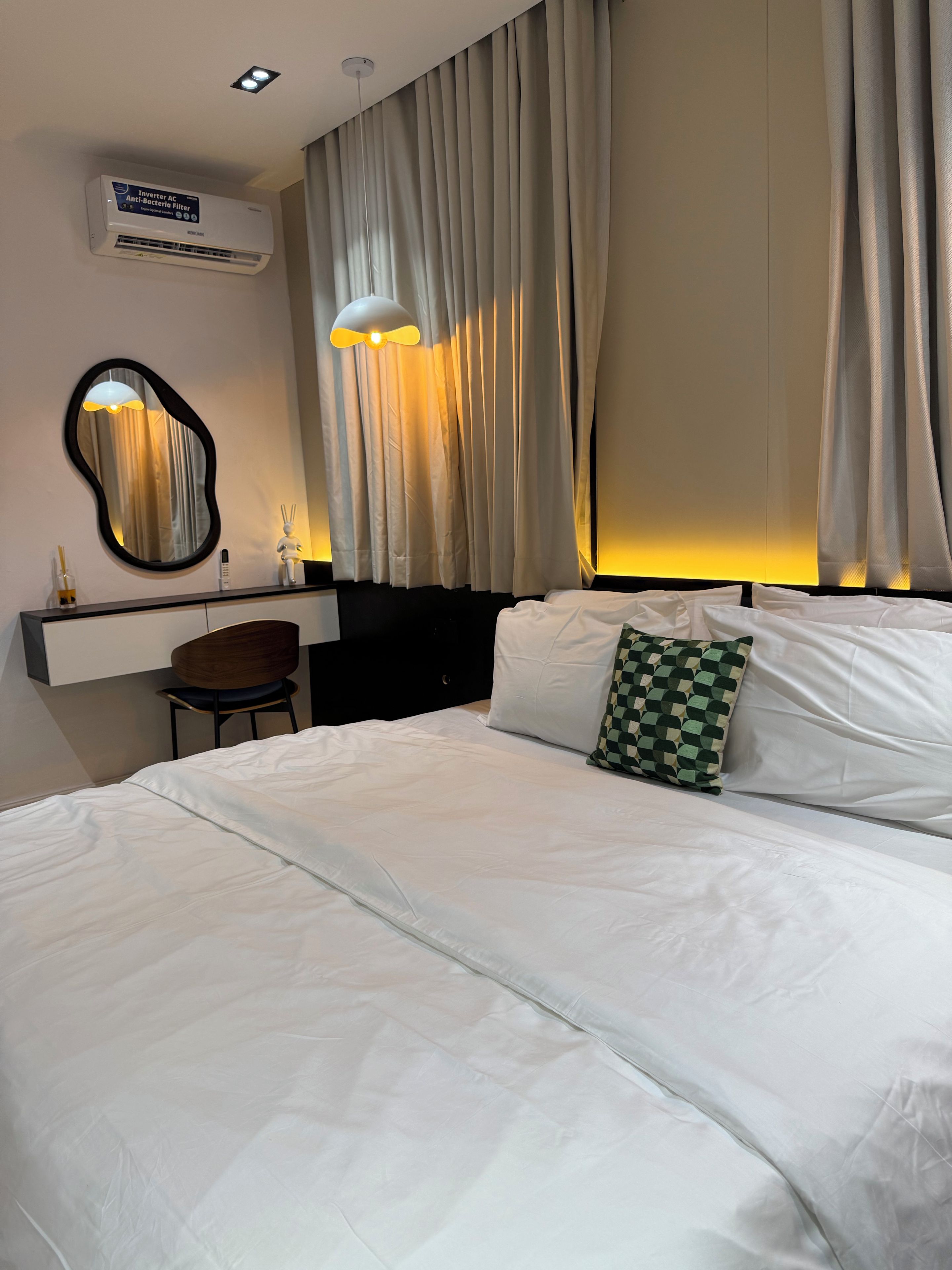 Ein Hotelzimmer mit einem Bett, einem Schreibtisch mit Stuhl, einem Spiegel und Vorhängen.