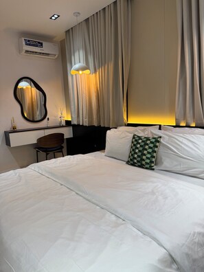 Ein Hotelzimmer mit einem Bett, einem Schreibtisch mit Stuhl, einem Spiegel und Vorhängen.