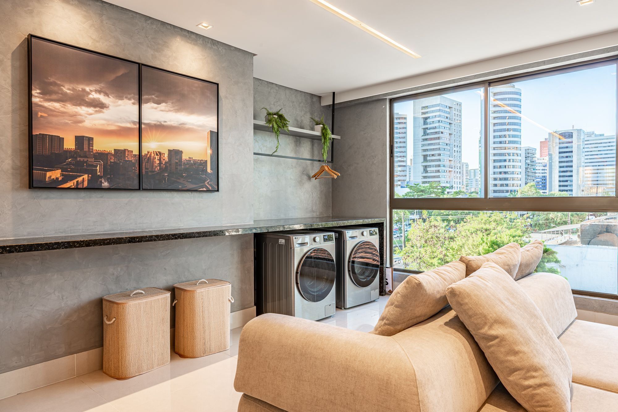 Una sala moderna con un ventanal grande, un sofá, una lavadora y vistas a un paisaje urbano.