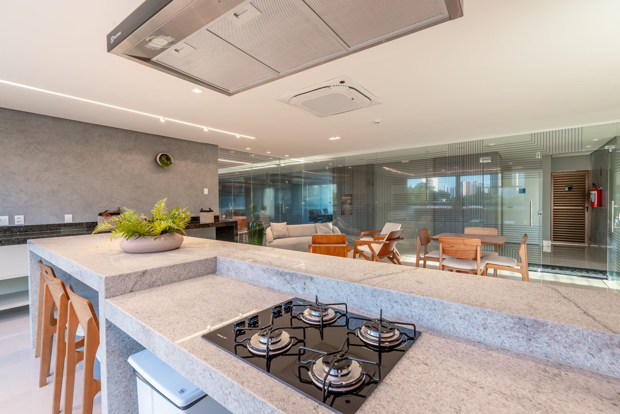 Una cocina moderna con estufa a gas, taburetes de bar y una zona de estar con sofá y sillones.