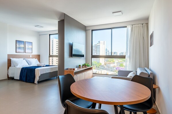 A modern hotel room with a bed, a dining table, and a TV. - Rooftop Agamenon #408 City View by Carpediem (Recife)