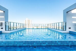 A rooftop infinity pool with a city view, surrounded by glass railings and white tiled walls. - Rooftop Agamenon #408 City View by Carpediem (Recife)