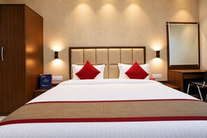 Een hotelkamer met een groot bed, twee nachtkastjes, een kledingkast en een bureau met stoel.
