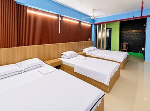 A hotel room with three wooden beds, a ceiling fan, and a wall with vertical wooden slats.