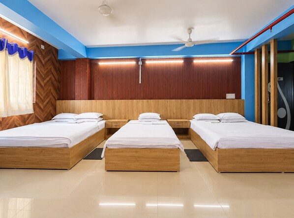 A hotel room with three wooden beds, a ceiling fan, and a modern design.