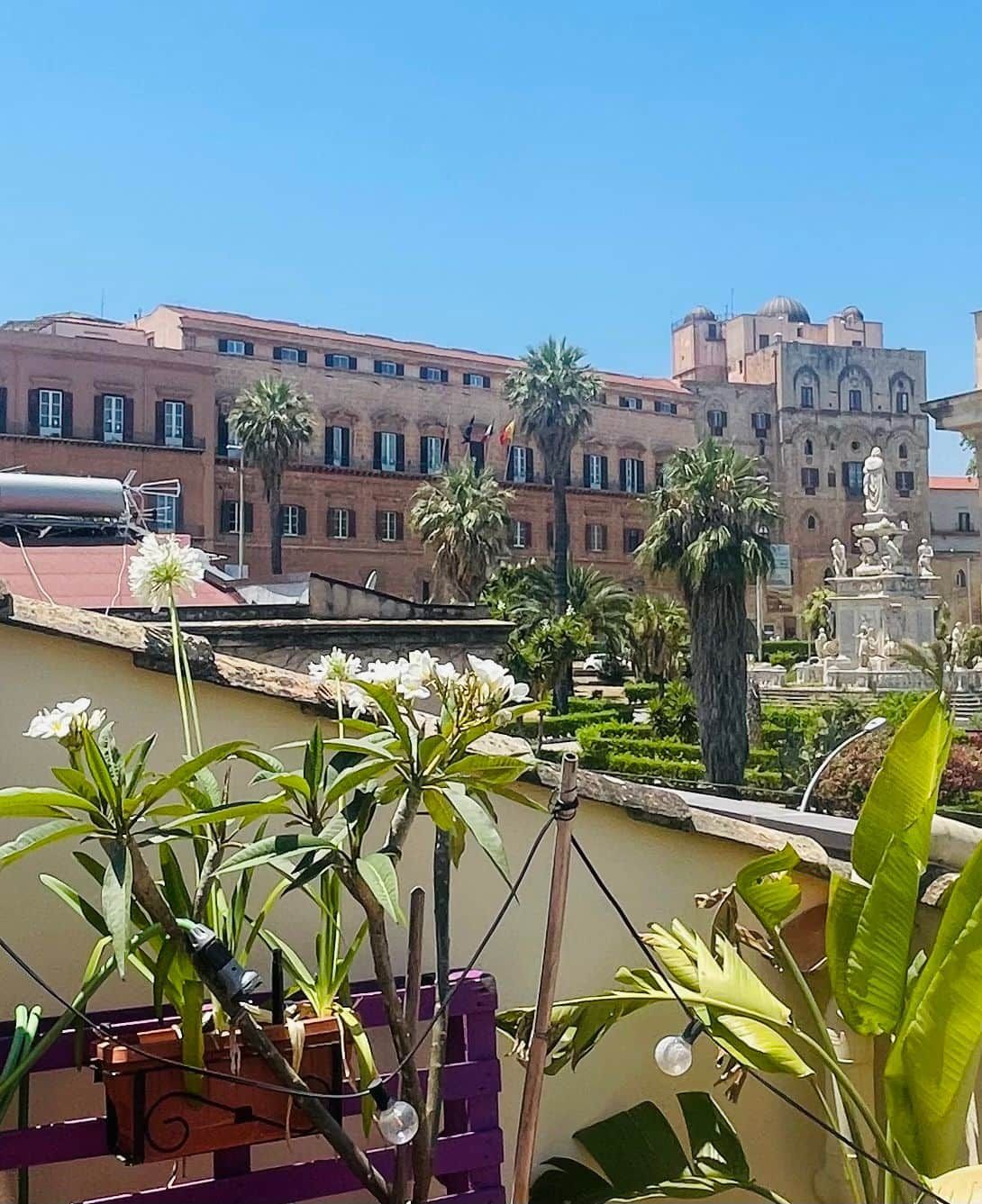 Un cortile con una fontana, palme e un edificio dall'architettura classica.