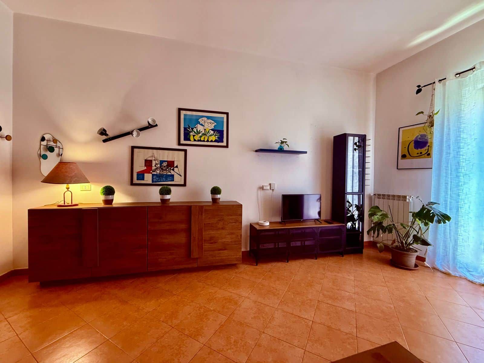 Ein Wohnzimmer mit Holzschrank, Fernseher und Topfpflanzen.