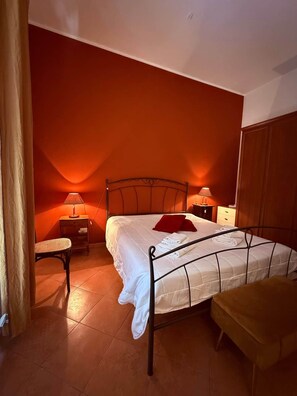 Ein Zimmer mit einem Bett, zwei Nachttischen, einem Sessel und einem Kleiderschrank.